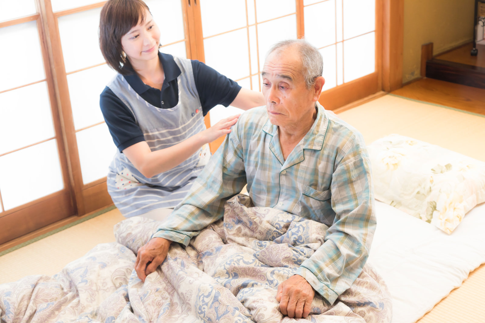 寝たきりの利用者の背中をさするスタッフによる身体介護の様子